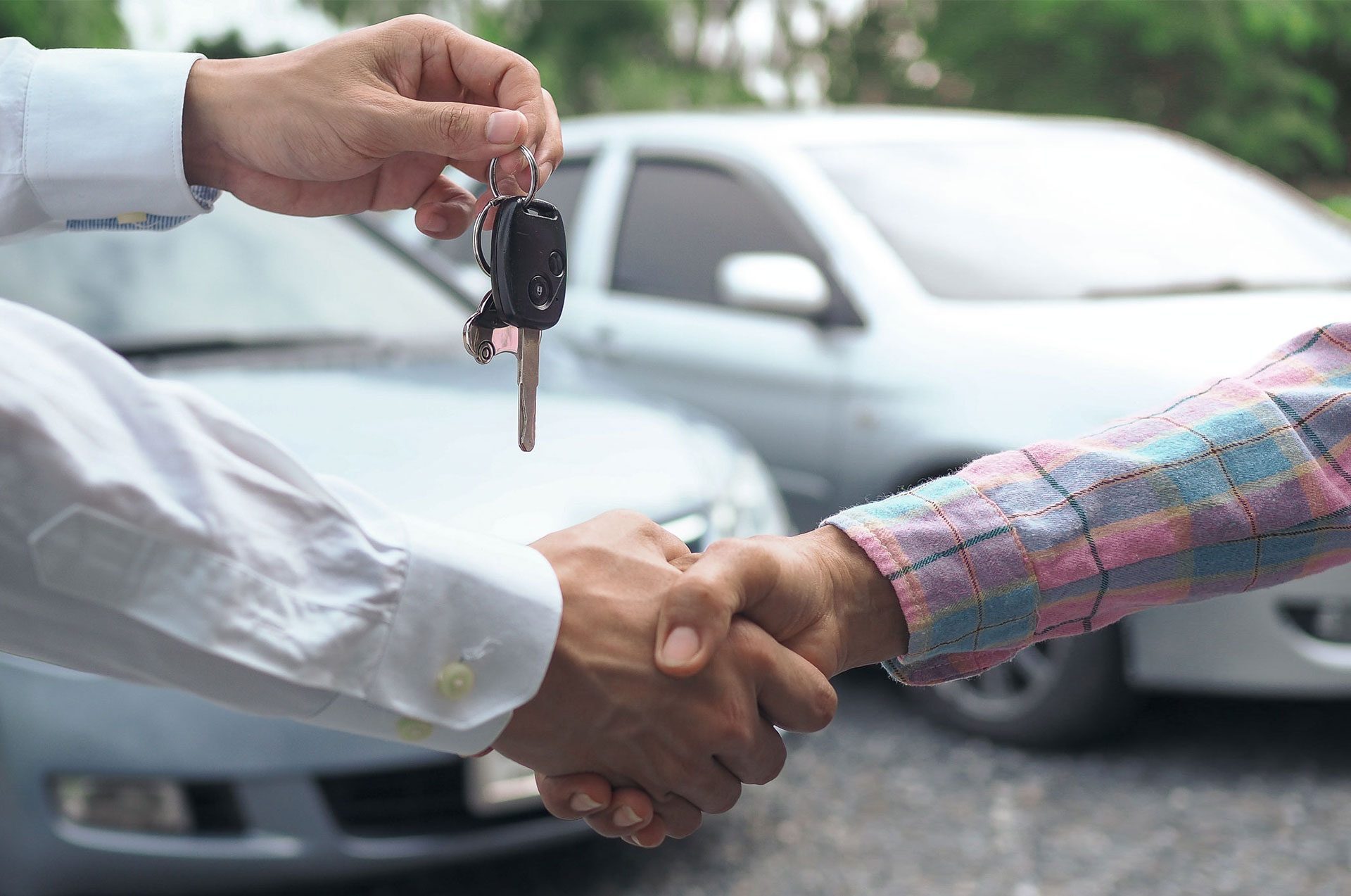 Zwei Personen schütteln sich die Hände und übergeben sich dank Privatkredit einen neuen Autoschlüssel.