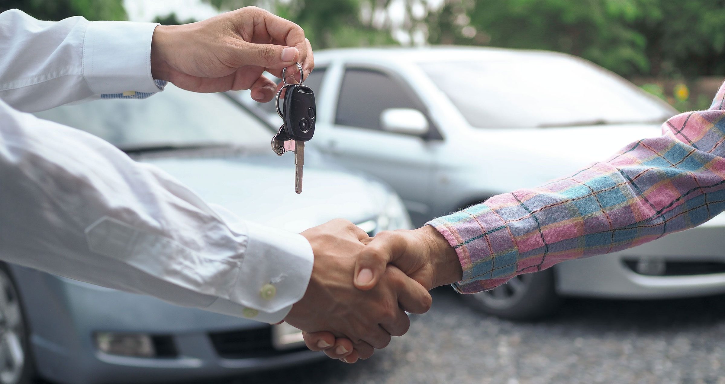 Zwei Personen schütteln sich die Hände und übergeben sich dank Privatkredit einen neuen Autoschlüssel.