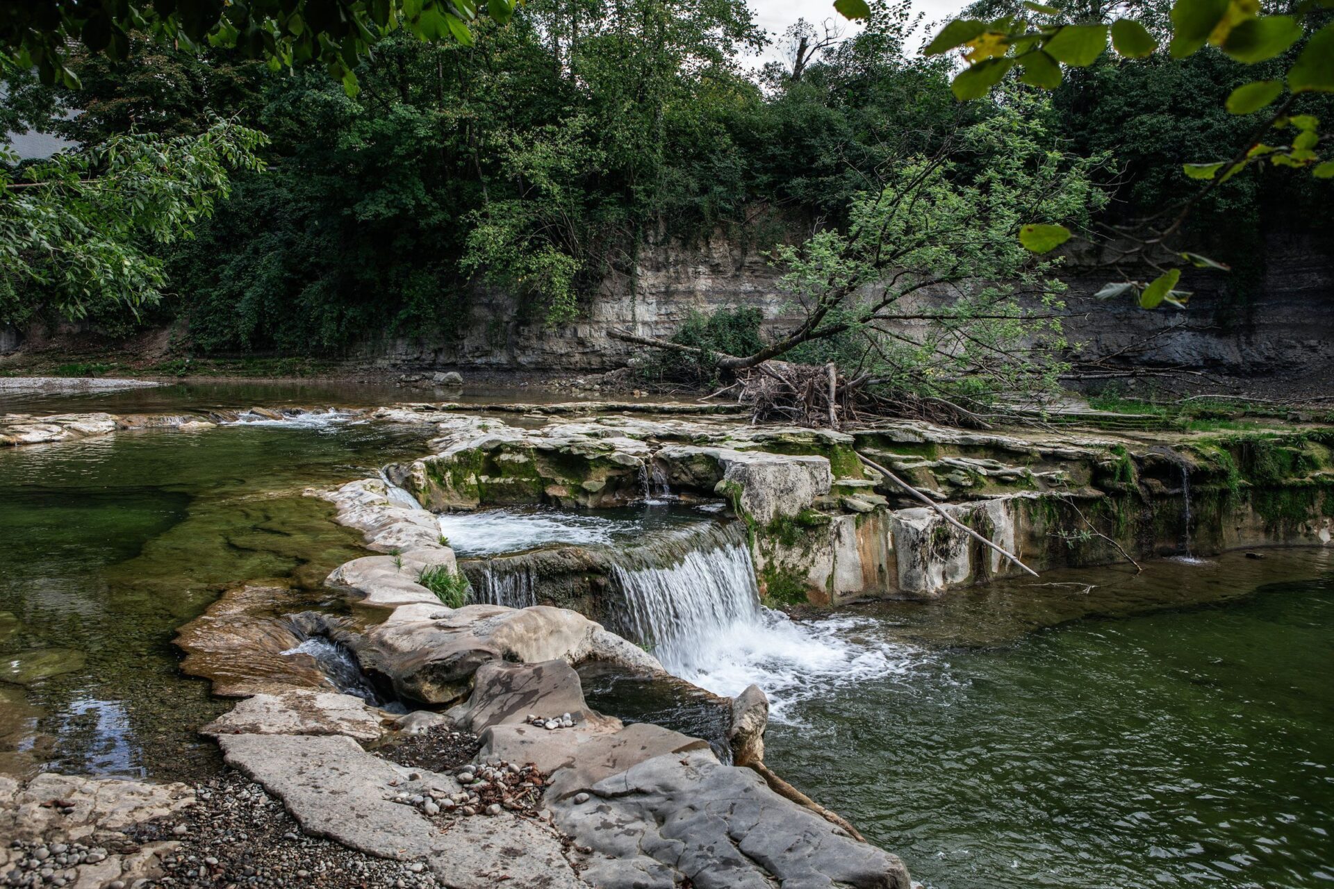 Ein Fluss mit einem Wasserfall, von Bäumen umgeben.