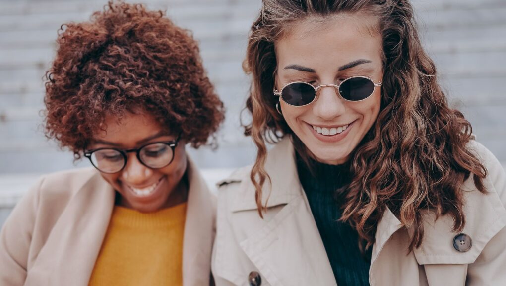 Zwei Frauen sitzen auf Treppenstufen und lesen die News.