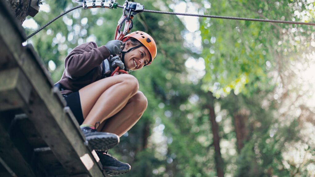 Eine Frau saust an einer Seilrutsche durch den Wald.