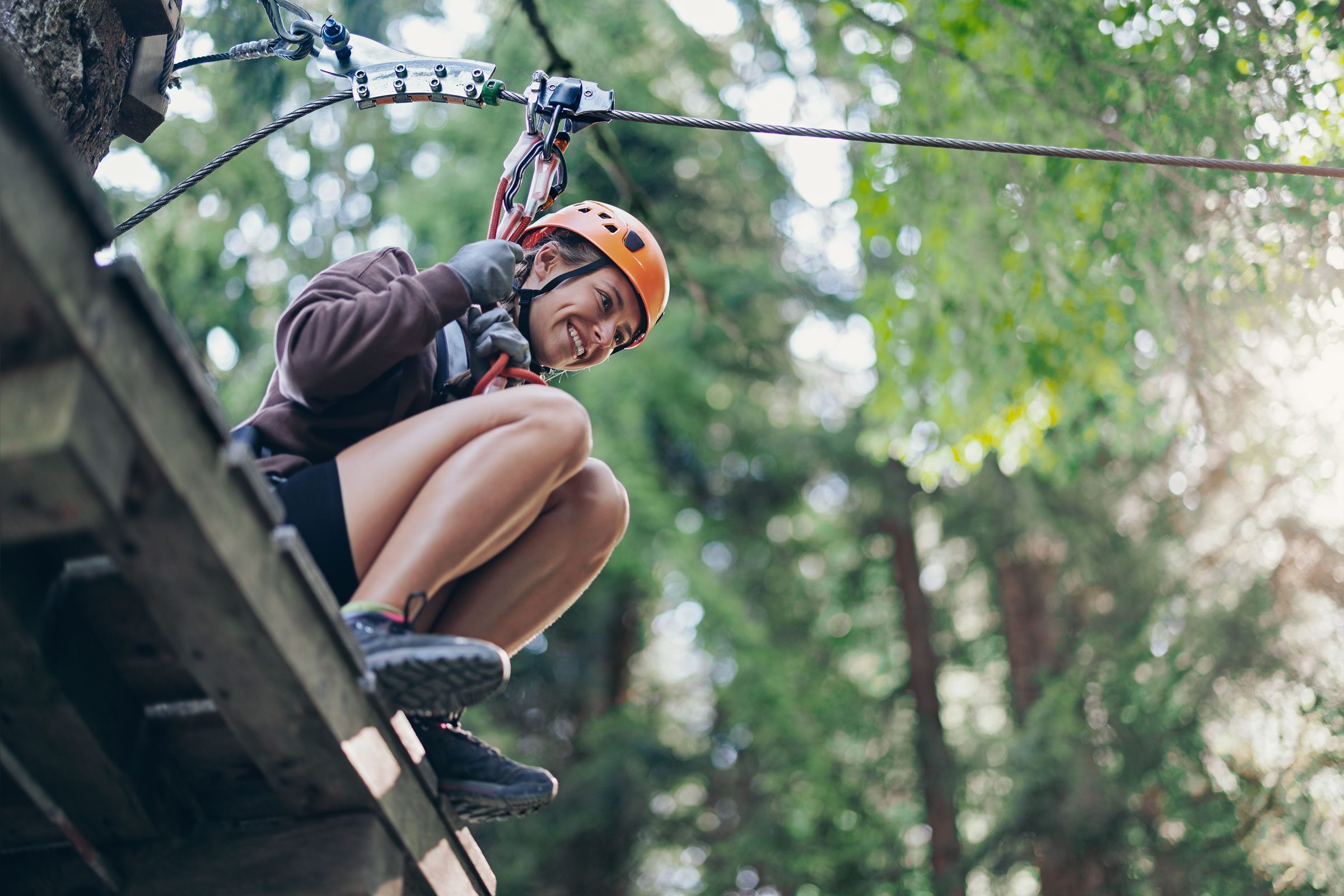 Eine Frau saust an einer Seilrutsche durch den Wald.