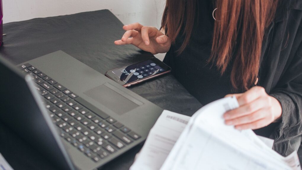 Eine Frau beschäftigt sich an ihrem Schreibtisch mit Zahlungen und E-Banking.